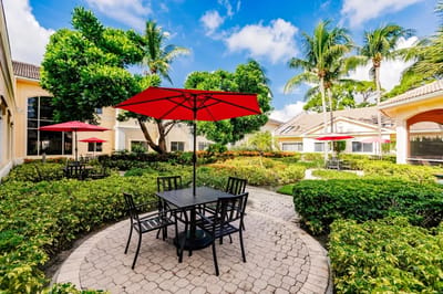 Outdoor patio with red umbrellas and greenery