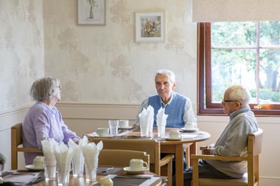 Residents enjoying conversation in a dining room