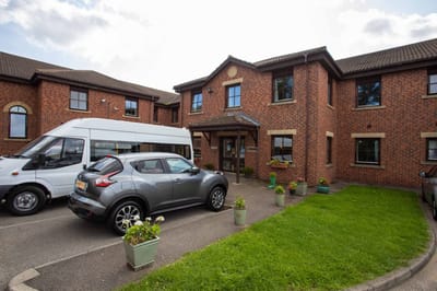 Front entrance of Marigold Nursing Home with vehicles