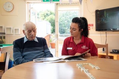 Senior resident and staff member reading together