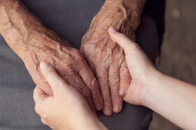 Gentle hands of an elderly person and caregiver together