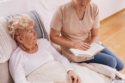 Caregiver reading to a resident in a cozy room