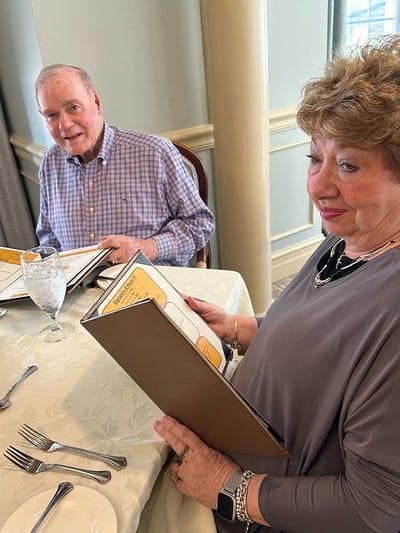Two residents reading menus at a dining table