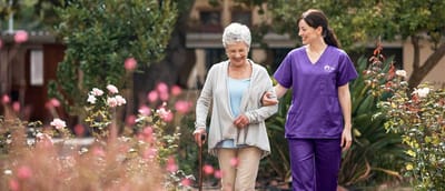 A caregiver assisting a senior in a garden