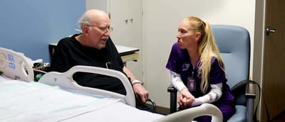 A resident conversing with a staff member in a care facility room