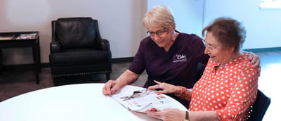 Staff and resident engaging over a magazine in a common area
