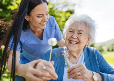 A caregiver with a senior resident outdoors, smiling.