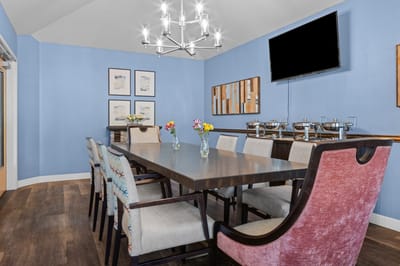Bright dining room with a large table and flowers.