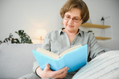 A senior woman reading a book in a cozy indoor setting