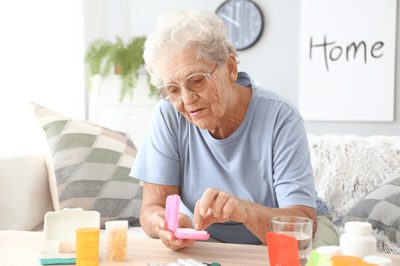 An elderly woman managing her medication in a bright room