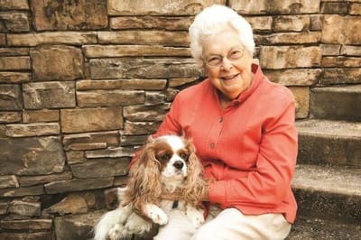 A senior woman smiling with a dog outside