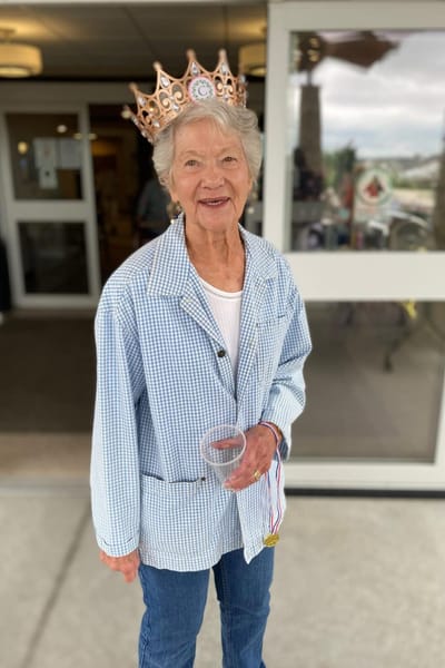 Resident wearing a crown and medal, smiling