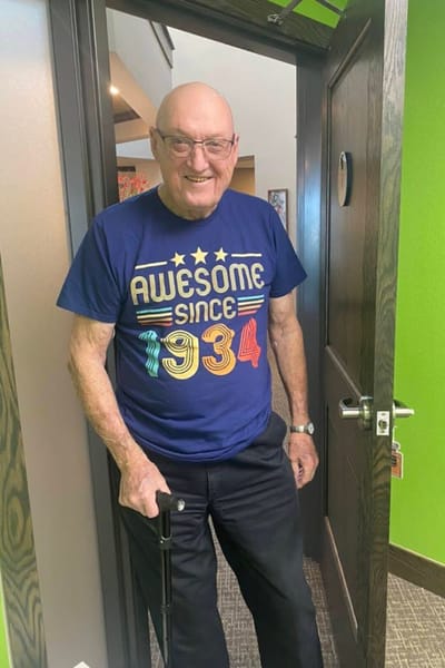 A resident in a colorful shirt standing at their door