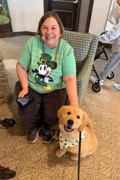 Resident enjoying time with a therapy dog in a common area