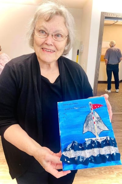 Resident showcasing a personal art project in a facility.