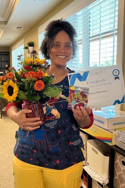 Staff member celebrating Employee of the Month with flowers and certificate