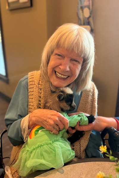 Resident joyfully holding a goat in a care facility