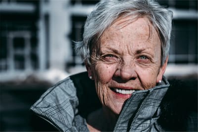 A smiling elderly woman in a coat