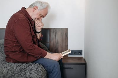 An elderly man reading a book in a cozy room