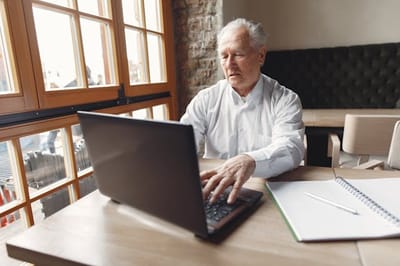 Elderly man using a laptop at a table