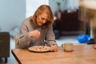 Senior woman enjoying a meal alone at a dining table