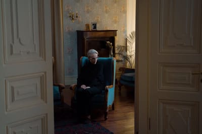 A senior resident sitting alone in a cozy chair
