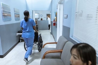 Healthcare worker pushing a wheelchair in a corridor