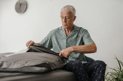Resident adjusting bedding in a room