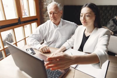Senior man and caregiver using a laptop together