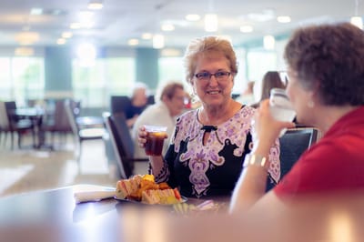 Residents enjoying sandwiches and drinks in the dining room