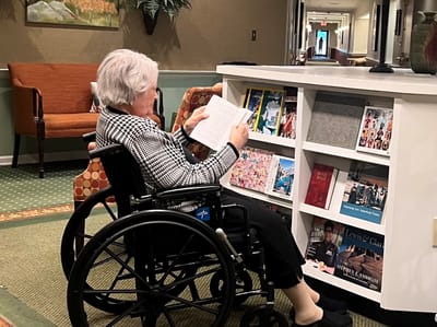 Resident reading in a common area with shelves