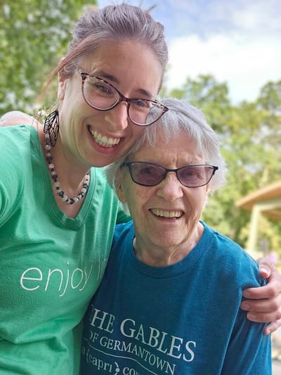 Caregiver and resident posing outdoors, smiling together