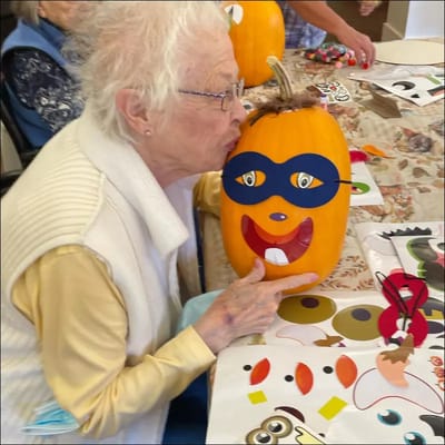 Elderly resident decorating a pumpkin during an activity