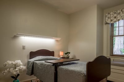 Interior view of a resident's room with a bed and lamp