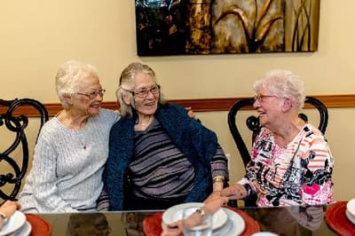 Three smiling residents enjoying time together in a common area