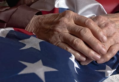 Elderly hands resting on an American flag