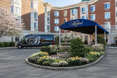Entrance of The Bristal Assisted Living with flowers and a shuttle van