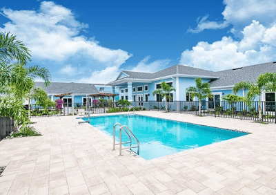 Outdoor pool area with buildings and palm trees