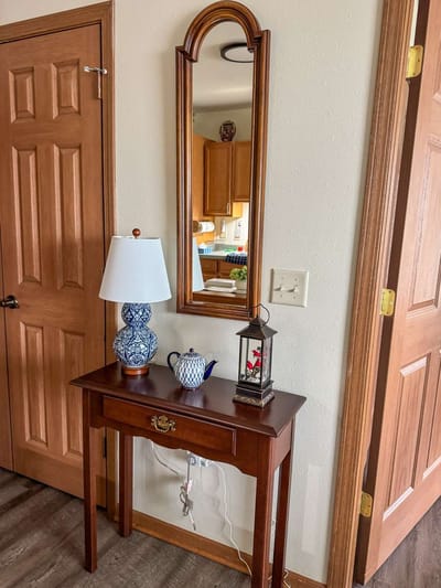 A decorative table with a lamp and mirror in a hallway
