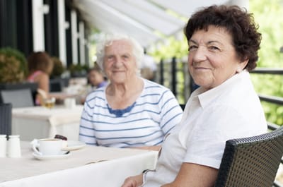 Two elderly women enjoying coffee outdoors