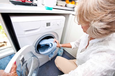 A resident doing laundry in a small laundry room