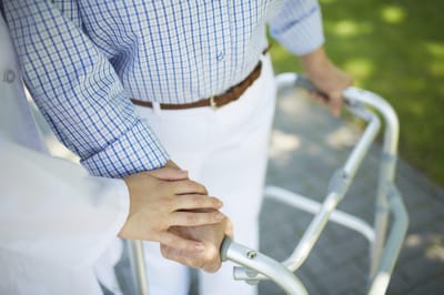 A caregiver assisting a senior with a walker outdoors