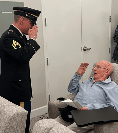 A soldier saluting an elderly resident in a cozy interior
