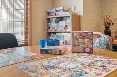 Puzzle pieces and boxes on a dining table in an activity room