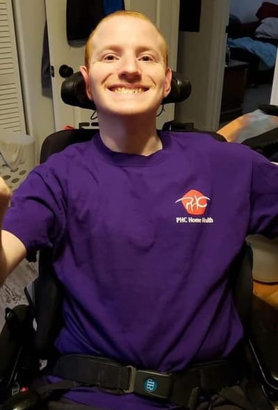 Resident in a purple shirt smiling in a wheelchair