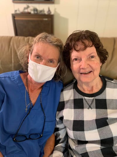A staff member and resident posing together in a cozy setting