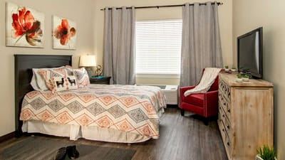A cozy resident room with bed and armchair