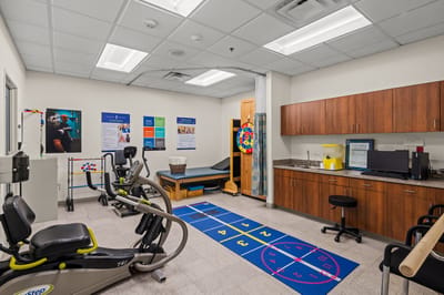 Physical therapy room with exercise equipment and colorful mat