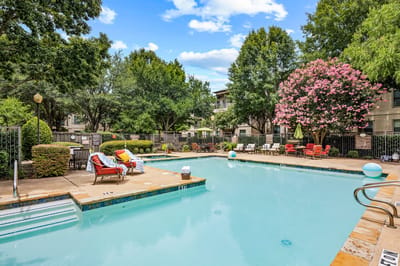 Pool area with lounge chairs and trees