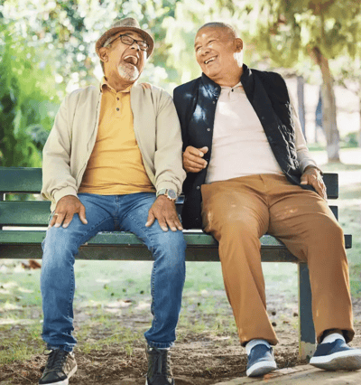 Two seniors laughing together on a park bench